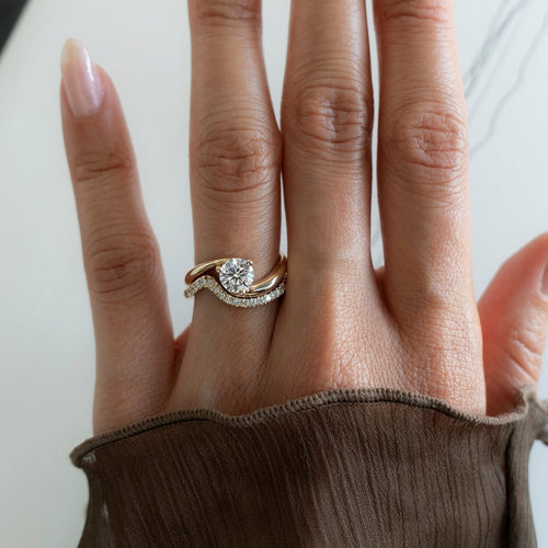 Round lab grown diamond swirl bridal set in yellow gold worn on the hand