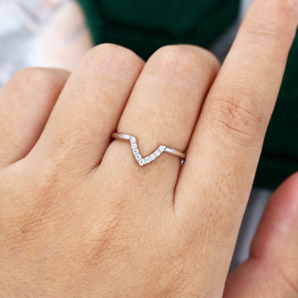 Round moissanite deep v-shaped curved wedding band, worn on the finger in white gold