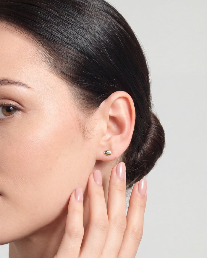 Model wearing round flush set oval disc lab grown diamond stud earrings, close up on the ear