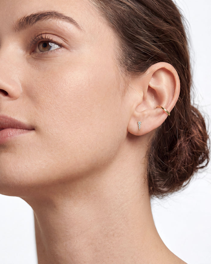 Model wearing round graduated triangle lab grown diamond stud earrings, close up on the ear