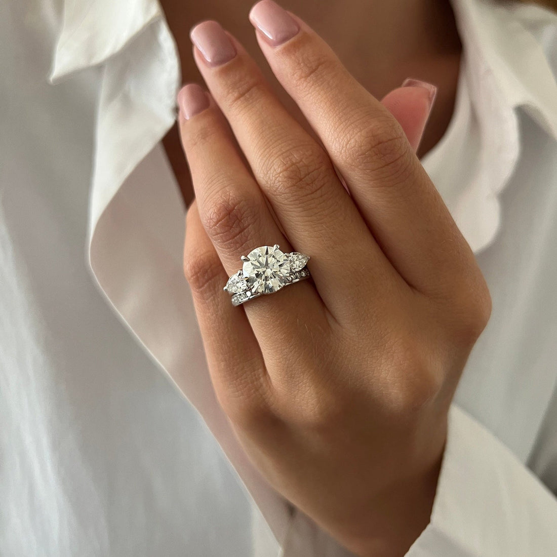 Round moissanite three stone ring with channel set band in white gold on the hand