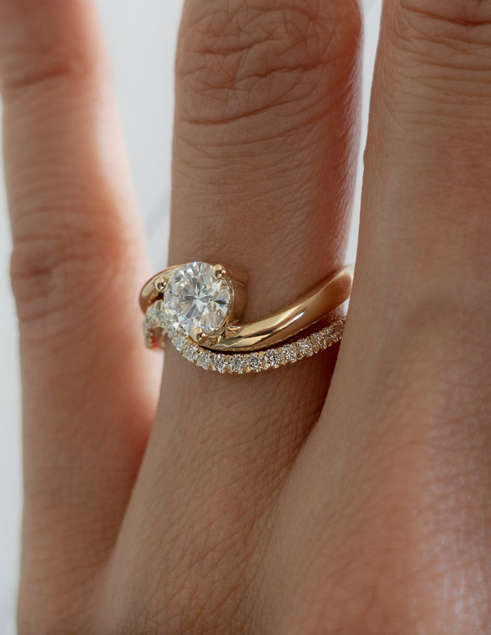 Close-up of round moissanite bypass engagement ring with curved pave wedding band