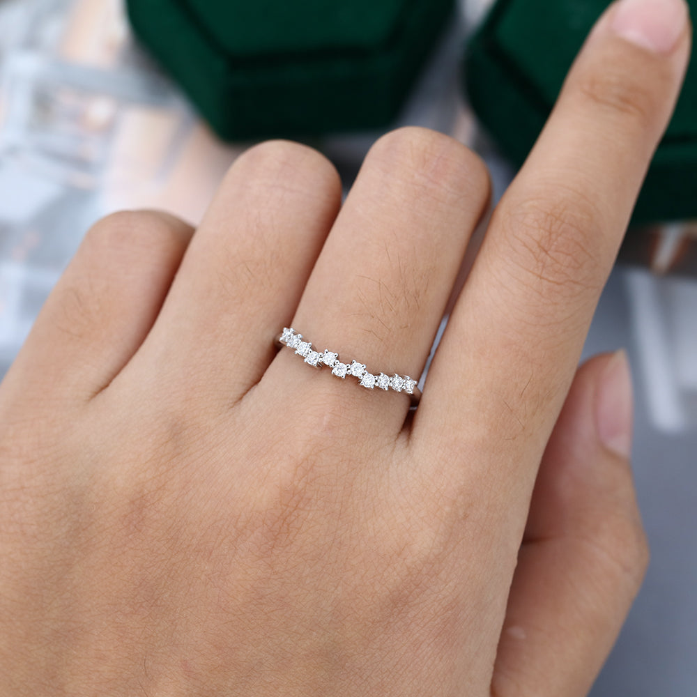 Round moissanite scattered cluster curved wedding band, worn on the finger in white gold