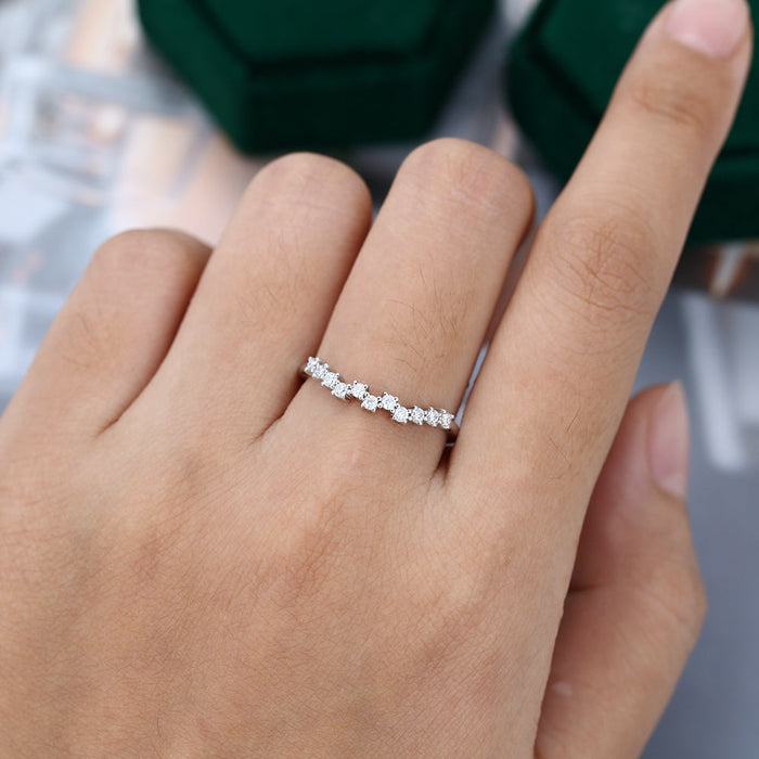 Round moissanite scattered cluster curved wedding band, worn on the finger in white gold