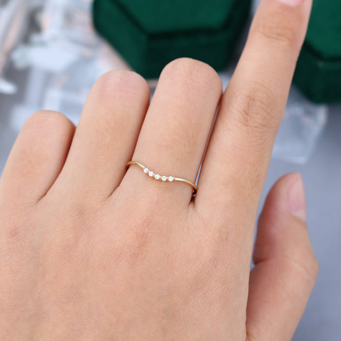 Round moissanite thin curved wedding band, worn on the finger in yellow gold