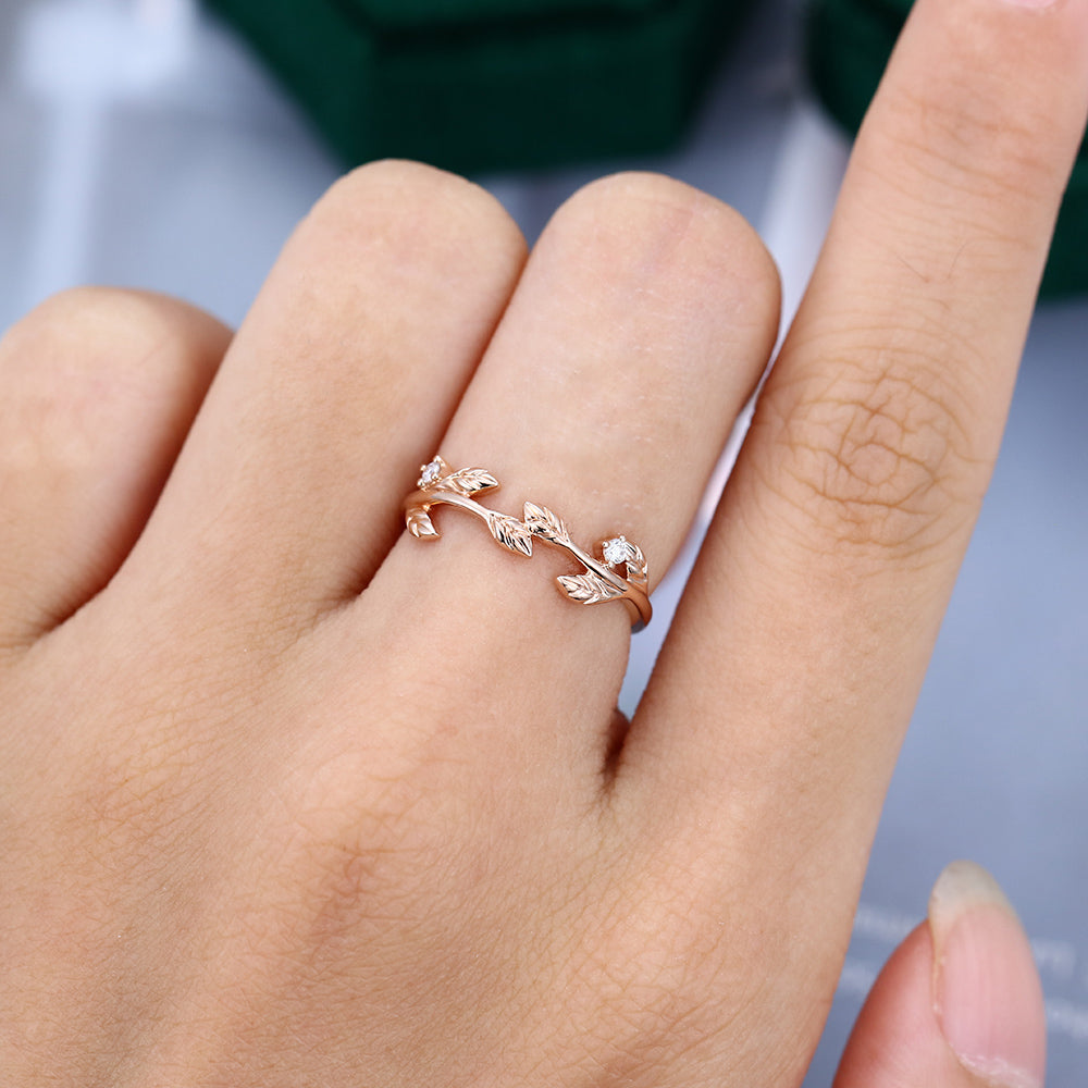 Round moissanite twig leaf wedding band, worn on the finger in rose gold