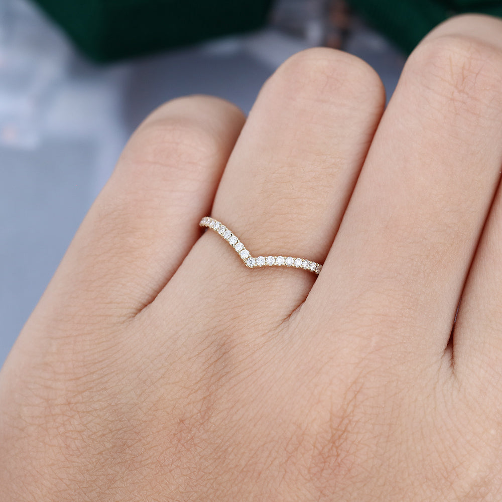 Round moissanite v-shaped pave curved wedding band, worn on the finger in yellow gold