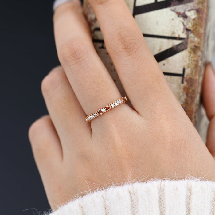 Round moissanite vintage milgrain wedding band, worn on the finger in rose gold